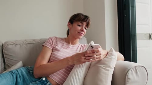 Woman Relaxing on Sofa Using Smartphone