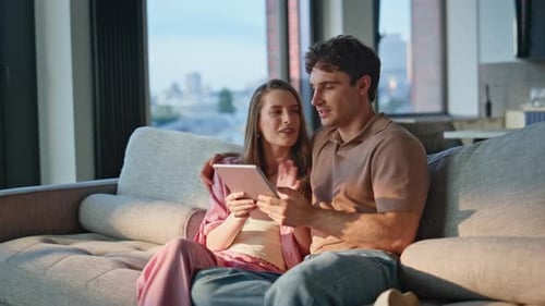 Romantic Pair Browsing Tablet on Comfortable Couch Closeup Smiling Couple