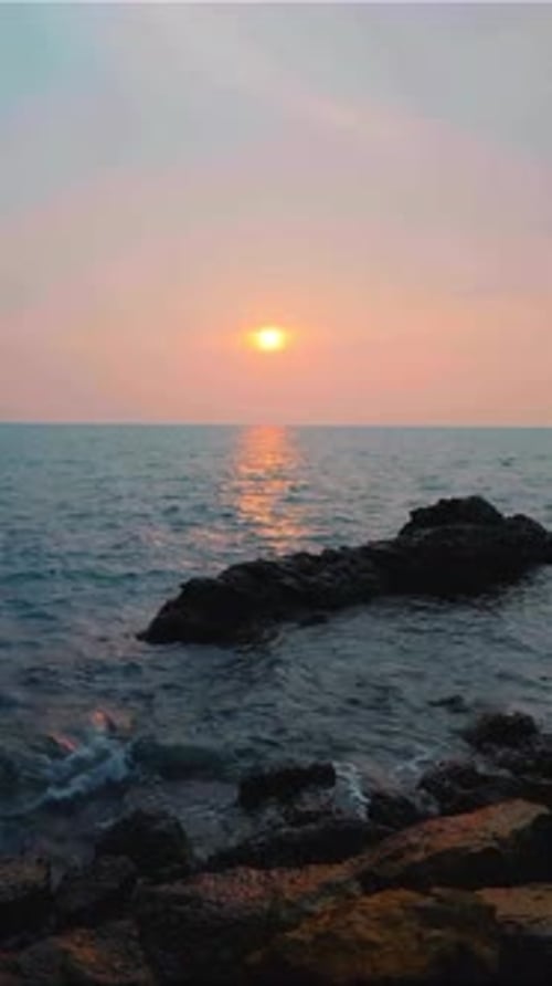 Sunset Over Rocky Shoreline with Gentle Waves