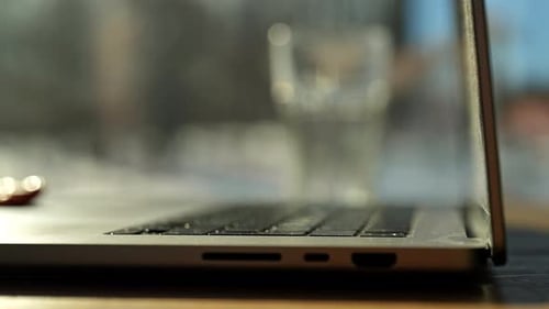 Nahaufnahme einer unbekannten jungen Frau, die den Deckel eines Laptops öffnet und anfängt zu tippen