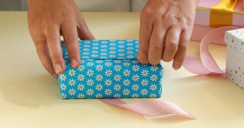 Hands unwrapping a gift in blue daisy paper