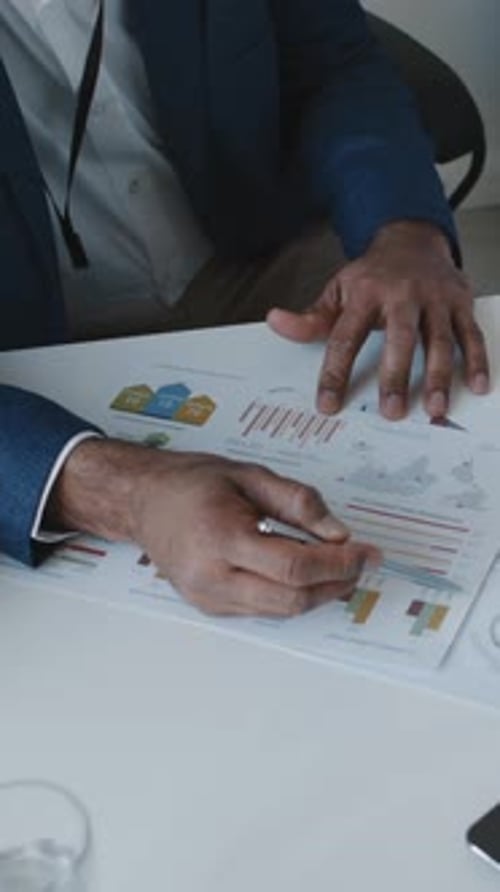 Hands of Male Executive Pointing to Financial Graphs while Speaking at Meeting