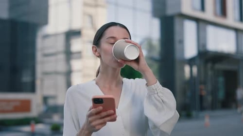 Young Woman Using Phone and Drinking Coffee Outdoors