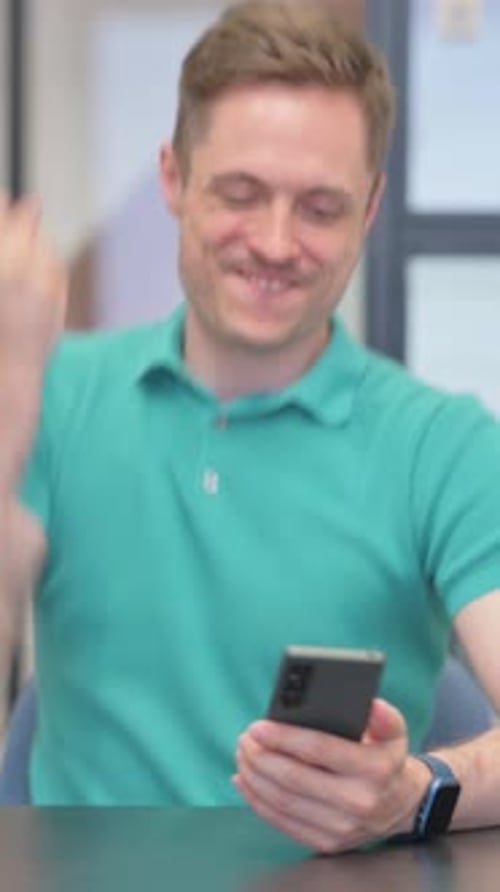 Man Smiling While Using Cellphone Indoors
