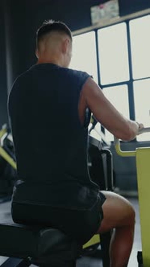 Muscular Man Working Out In Gym On Strength Training Equipment