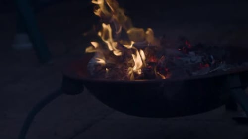 Newspaper being thrown into a fire, causing a small fireball explosion in slow motion