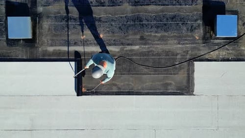 Roofer applying torch to bitumen membrane on torch down roof