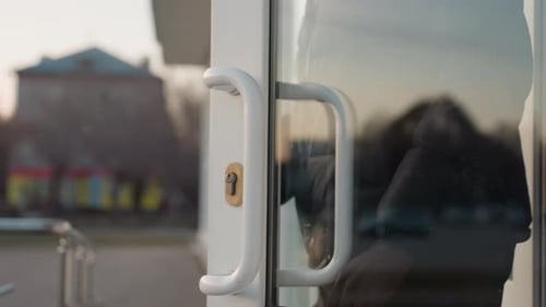 Close Up of Hand Pulling Glass Door Handle to Exit Building