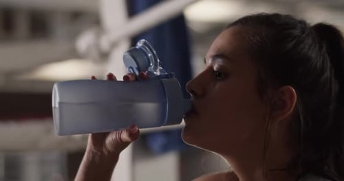 Woman Drinking Water After Workout in Gym