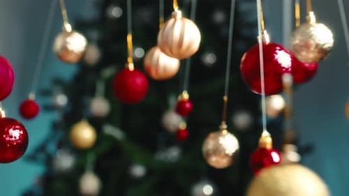 Festive Ornaments Hang in Front of Christmas Tree