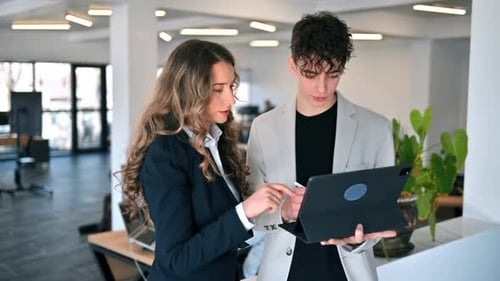 Business session in an office. Woman and a young man discussing business affairs, tablet. Slow motio