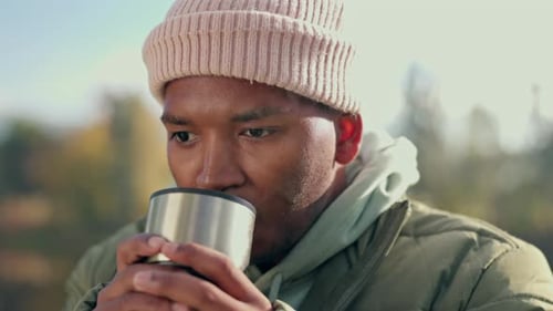 Man Drinking from Thermos Outdoors on Sunny Day