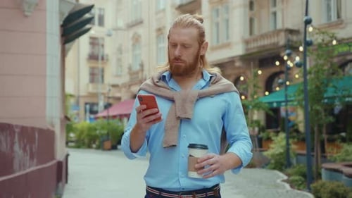 Man Walks on City Street Using Phone