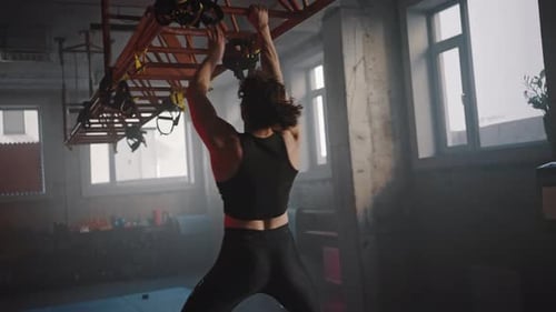 Rear View of Athletic Woman with the Help of Hands Moves on the Crossbars