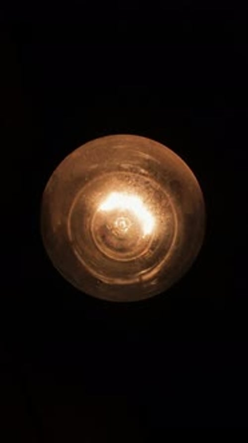 Old Flashing Light Bulb on Black Background Close Up Vertical Video