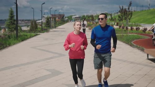 A Man and a Woman Run Around a Beautiful and Wellmaintained City Park Summer Cardio Training is