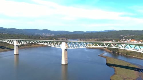 railway bridge over the ulla river, the village, industrial buildings and the forested mountains in