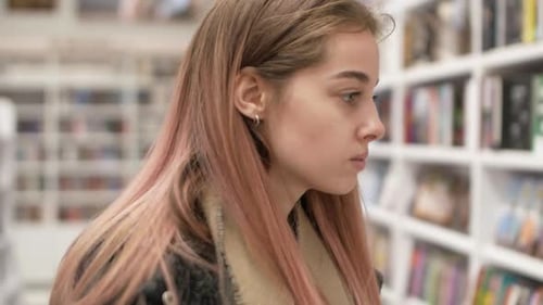 Retrato de jovem atraente de cor rosa escolhendo livro na livraria