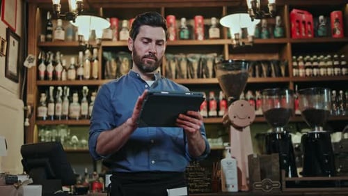 Man with Welcoming Smile Working on Tablet While Standing at Bar Counter