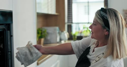 Glückliche junge Mutter und entzückte Oma mittleren Alters in moderner Küche beim Backen hausgemachter Kekse