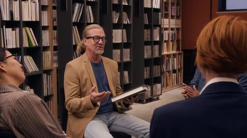 People Listening to Speaker During Book Club Gathering in Library