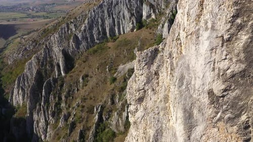 Flying through vertical limestone walls in a deep gorge, canyon, rock climbing aerial