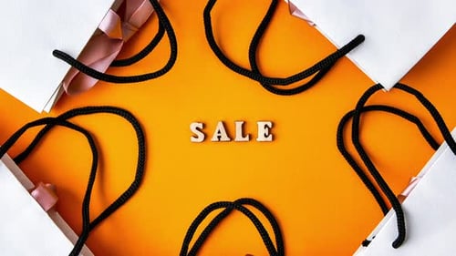 Zoom in Out Wooden Letters Text SALE with Packaging Bags in Front Yellow Background Top View Flat