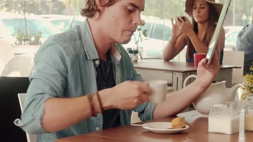Medium Shot Of Casual Man Using Touch Screen Tablet Computer In Cafe.