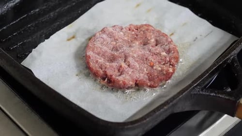 231q. Frying patties in a pan to prepare a burger