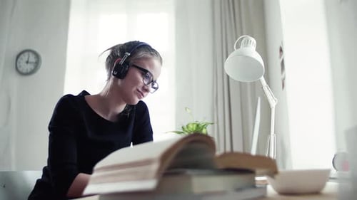 Young Woman Studying with Headphones at Desk Indoors