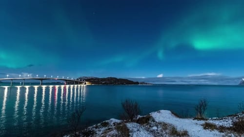 time lapse of northern lights over sommaroy village on island and bridge during winter night in norw