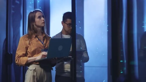 In a Hightech Server Room a Man and Woman Analyze Data Intently