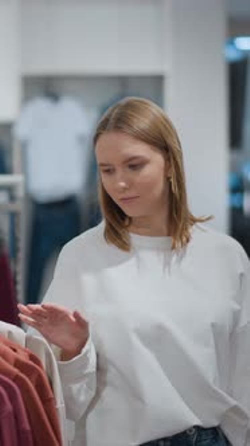 Woman Browsing Clothing Store Checking Tops on Sale