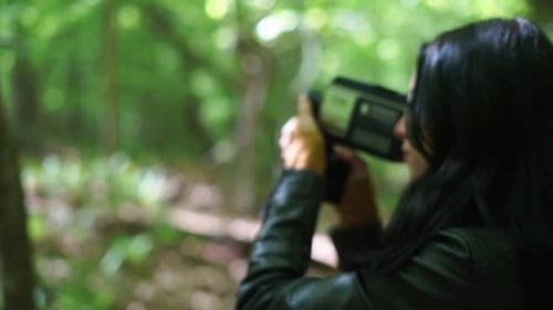 Linda mulher amadora gravando em uma antiga câmera de vídeo de filme na floresta - cardan giratório de perto