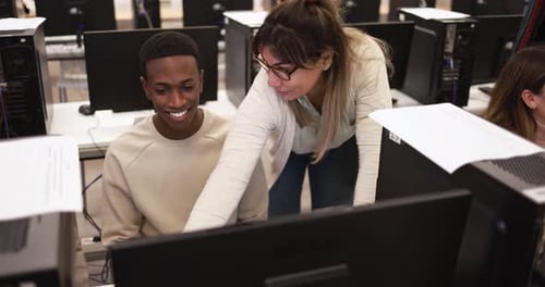 Mature Teacher Working with Multiracial Students Inside Computer Classroom at University Academic