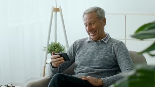 Man Relaxing at Home Looking at Mobile Phone
