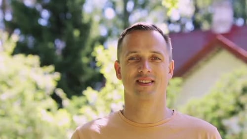 Man Smiling in front of a House
