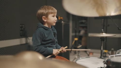 Little Boy Enthusiastically Playing the Drums in a Music Studio
