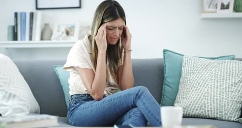 Woman With Headache Sits on Sofa