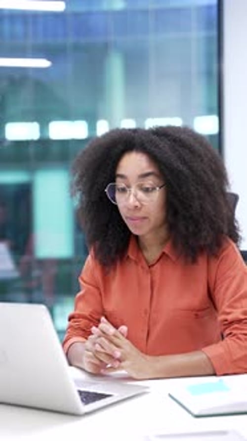Confident african american businesswoman talking on video call using laptop sitting in office.