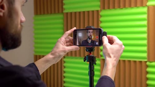 Ein junger Blogger verbindet ein drahtloses Mikrofon mit seinem Telefon, um Videos aufzunehmen