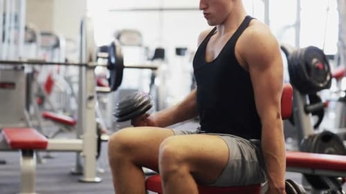 Sport, Bodybuilding, Lifestyle And People Concept - Young Man With Dumbbells Flexing Muscles In Gym