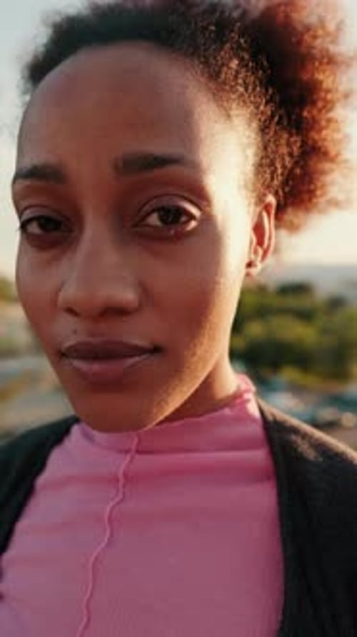 Vertical video, Close up, young woman with curly hair looking at camera