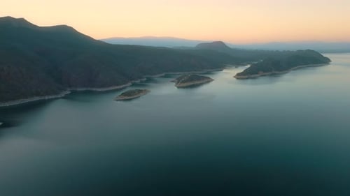 Aerial drone flying over a lake, water dam, with mountains at sunrise. Beautifull dreamy landscape