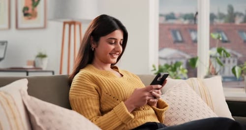 Woman Relaxing on Sofa Using Smartphone