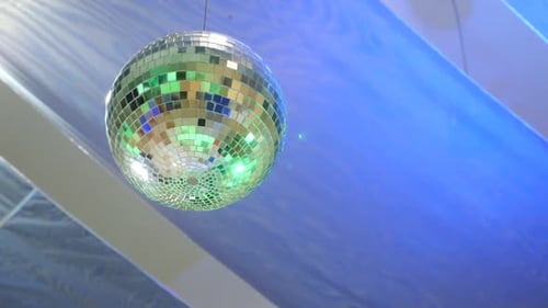 S62. The mirror ball rotates illuminated by colored light. Nightclub disco atmosphere.