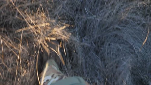 Point de vue des jambes d'une jeune fille militaire en chaussures militaires faisant du jogging dans un champ non cultivé