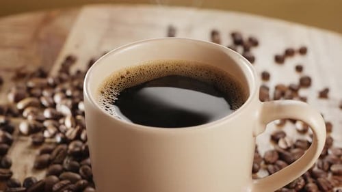 Steaming Coffee in a Cup with Coffee Beans