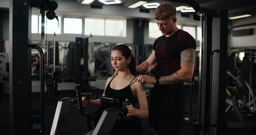 Woman Using Rowing Machine with Gym Instructor