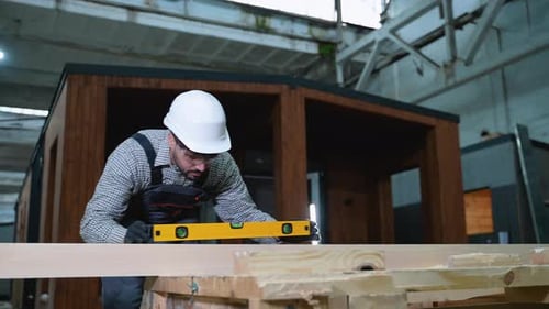 Ouvrier du bâtiment vérifiant le niveau de la planche de bois dans l'atelier